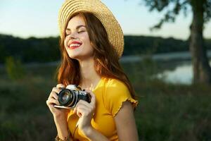 bonito mujer con cámara en naturaleza Fresco aire sombrero rojo labios pasatiempo foto