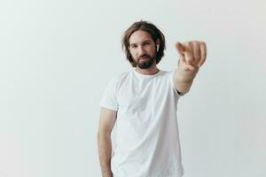 happy man listening to music and smiling in a white t-shirt on a white background and pointing a finger at the screen at the camera photo