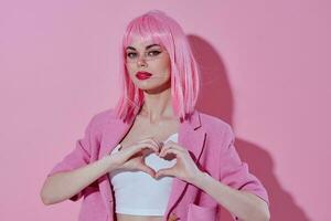 Beautiful fashionable girl hold hands in the shape of a heart with a pink jacket pink background photo