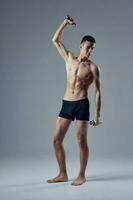 deportivo hombre posando en negro pantalones cortos con pesas en manos rutina de ejercicio aptitud foto