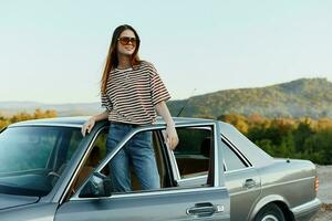 A young woman driver looks out of the car at the autumn landscape and smiles satisfactorily photo