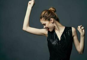 Elegant lady in a black dress on a gray background gestures with her hands emotions surprise joy photo