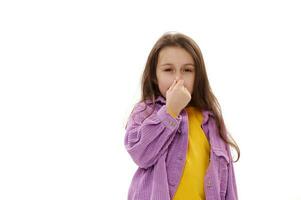 Cute Caucasian child girl is closing her nose with her hand, feeling bad from the smell, isolated on white background photo