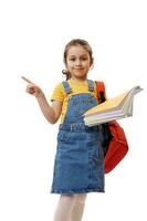 Schoolgirl, first grader holding books, pointing finger at copy space on white background, smiling, looking at camera photo
