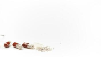 Still life with enteric capsules spilling out from gel translucent capsule, isolated on white background. Copy ad space photo