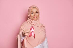 detalles rosado satín conciencia cinta en musulmán mujer manos. octubre conciencia mes campaña, luchando pecho cáncer foto