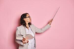 Confident pregnant woman, professor, teacher in stylish spectacles, points to copy space with pointer, explaining lesson photo