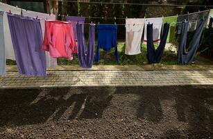 Washed clothes hanging on a rope, drying in the open air in the backyard of the a countryside house photo