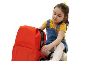 de cerca retrato de caucásico adorable pequeño niño, Chica de escuela con naranja mochila, aislado terminado blanco antecedentes. foto