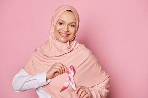 musulmán mujer en hiyab, vistiendo rosado satín cinta, apoyos cáncer pacientes sobrevivientes mundo pecho cáncer conciencia día foto