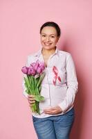embarazada mujer con satín cinta y tulipanes racimo, secundario cáncer pacientes conciencia Campaña luchando pecho cáncer foto