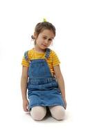 Caucasian lovely little child girl blinking, sitting on her knees on isolated white background photo