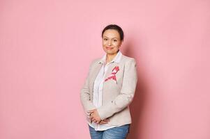 Positive woman, wearing pink satin ribbon, showing her support for Cancer patients. Breast Cancer Day Awareness campaign photo