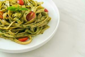 fettuccine spaghetti pasta with pesto sauce and tomatoes photo