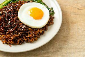 dried Korean spicy black sauce instant noodles with fried egg and kimchi photo