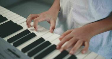 Nahansicht Hand von kreativ asiatisch Junge mit künstlerisch Kompetenzen nehmen Musik- Lektionen online während ein Video Anruf und spielen das Klavier beim heim. Musik, Hobby und Lebensstil Konzepte.