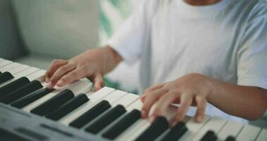 Nahansicht Hand von kreativ asiatisch Junge mit künstlerisch Kompetenzen nehmen Musik- Lektionen online während ein Video Anruf und spielen das Klavier beim heim. Musik, Hobby und Lebensstil Konzepte.