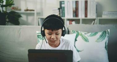 Mano disparo, creativo asiático chico vistiendo auricular con artístico habilidades tomando música lecciones en línea durante un vídeo llamada y jugando el piano a hogar. música, pasatiempo y estilo de vida conceptos. video