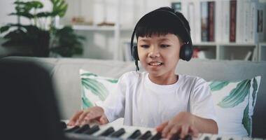 handhållen skott, kreativ asiatisk pojke bär hörlurar med konstnärlig Kompetens tar musik lektioner uppkopplad under en video ring upp och spelar de piano på Hem. musik, hobby och livsstil begrepp.