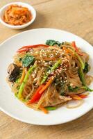 japchae or stir-fried Korean vermicelli noodles with vegetables and pork topped with white sesame photo