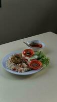 Rice with chicken and vegetables in a white plate on the table photo