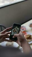 mujer tomando un foto de desayuno con un teléfono inteligente en un café