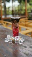 grated cucumber ice with red syrup in a long glass photo