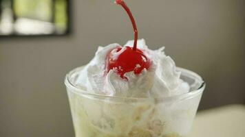 Iced chocolate avocado with whipped cream and cherry in a glass on table photo