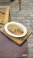 close up of a bowl of chicken soup on a wooden table. photo