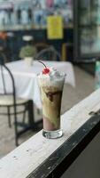 aguacate chocolate con azotado crema y Cereza en un vaso en mesa foto