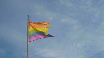 Gay stolthet regnbåge flagga vinka på blå himmel bakgrund. symbol av de HBTQ gemenskap på en stolthet. mänsklig rättigheter, likvärdig rättigheter, fred och frihet. Stöd lgbtq gemenskap video