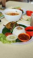 Rice with meat and vegetables in a white plate on the table photo