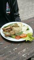 A la parrilla pollo con arroz y vegetales en el de madera mesa en el restaurante foto