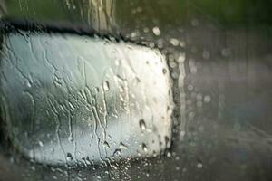 Raindrops on the car window and rearview mirror. Driving in the rain. sad vibe photo