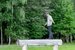 un hombre tiene divertido en el parque y camina en un registro, comprobación su equilibrar foto