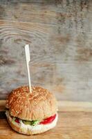 big beef burger with buns with sesame seeds on wooden background, close up photo