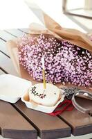 Bento cake with a candle with a bouquet of pink gypsophila on a wooden table, in a cafe. Little surprise for a girl's birthday photo