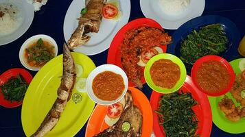 Seafood dish served on the table and plate from above with different kind of dish from fried fish barracuda, snapper, tuna jaws, and also mix of tropical vegetables photo