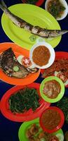 Seafood dish served on the table and plate from above with different kind of dish from fried fish barracuda, snapper, tuna jaws, and also mix of tropical vegetables photo