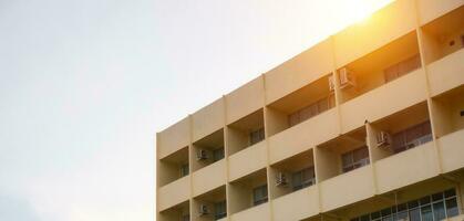 side view of yellow concrete building Intersect the orange sun. photo