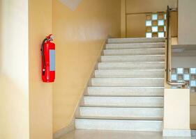 un fuego extintor cuelga arriba el escaleras. fuego la seguridad concepto. foto