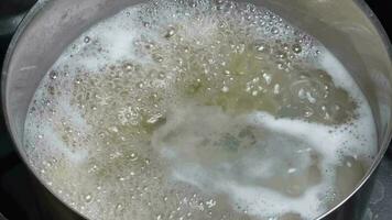 White foam in a pot of boiling water on a stove. video