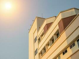 side view of yellow concrete building Intersect the orange sun. photo