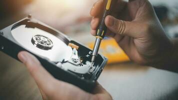 Close up of hard disk internal mechanism hardware. HDD in hand with a screwdriver photo