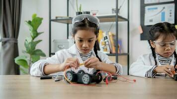 Asian students learn at home in coding robot cars and electronic board cables in STEM, STEAM, mathematics engineering science technology computer code in robotics for kids concept. photo