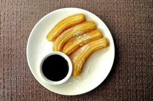 Freshly made Spanish crispy churros with dark chocolate dipping sauce photo