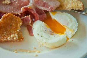 Inglés desayuno - escalfado sabroso medio cocido huevos y tocino foto