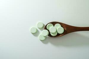 Group of medicine pills and antibiotics, White medical tablets, light green, with wooden spoon, with copy space. photo