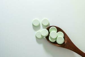 grupo de medicina pastillas y antibióticos, blanco médico tabletas, ligero verde, con de madera cuchara, con Copiar espacio. foto