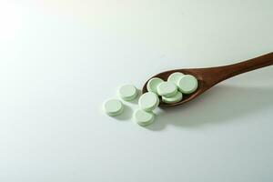 grupo de medicina pastillas y antibióticos, blanco médico tabletas, ligero verde, con de madera cuchara, con Copiar espacio. foto